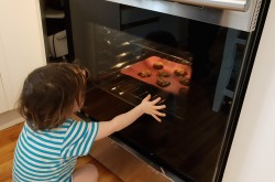 Un jeune enfant regarde cuire les biscuits dans un four.